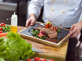 Image showing closeup of Chef hands serving beef steak