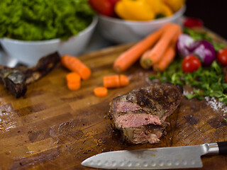 Image showing Juicy slices of grilled steak on wooden board