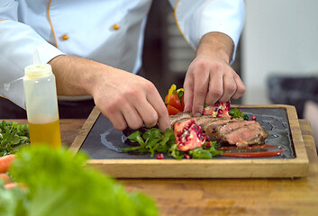 Image showing closeup of Chef hands serving beef steak