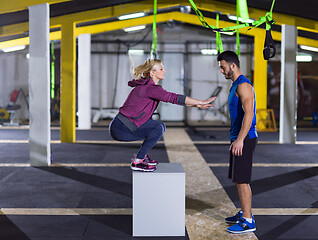 Image showing woman working out with personal trainer jumping on fit box