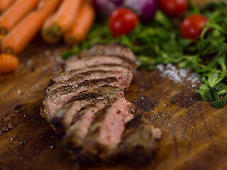 Image showing Juicy slices of grilled steak on wooden board