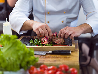 Image showing closeup of Chef hands serving beef steak