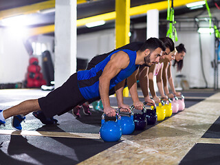 Image showing young athletes doing pushups with kettlebells