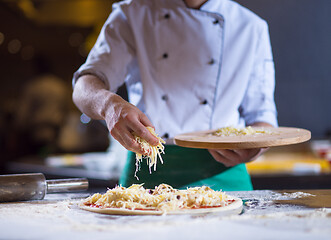 Image showing chef sprinkling cheese over fresh pizza dough