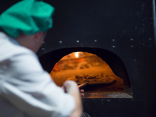 Image showing chef putting delicious pizza to brick wood oven