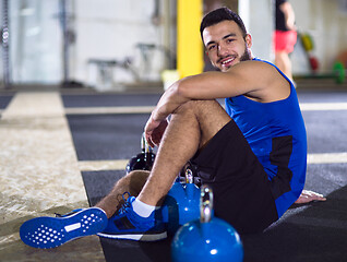 Image showing young athlete man sitting on the floor and relaxing