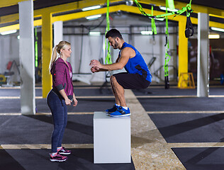 Image showing woman working out with personal trainer jumping on fit box