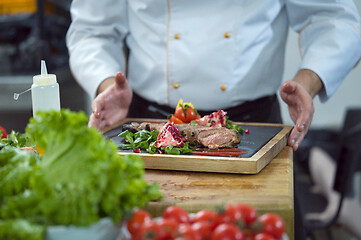 Image showing closeup of Chef hands serving beef steak