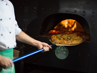 Image showing chef removing hot pizza from stove