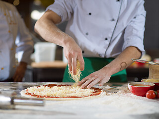 Image showing chef sprinkling cheese over fresh pizza dough