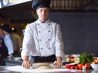 Image showing chef preparing dough for pizza with rolling pin