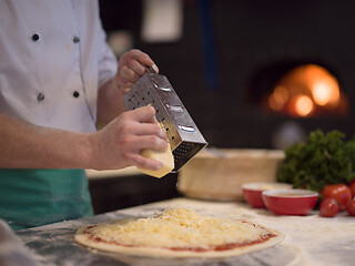 Image showing chef sprinkling cheese over fresh pizza dough