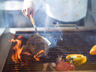 Image showing chef cooking steak with vegetables on a barbecue