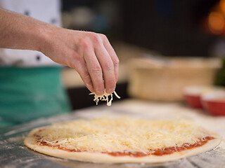 Image showing chef sprinkling cheese over fresh pizza dough