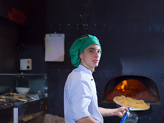 Image showing chef putting delicious pizza to brick wood oven