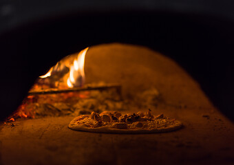 Image showing chef putting delicious pizza to brick wood oven