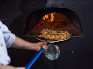 Image showing chef removing hot pizza from stove