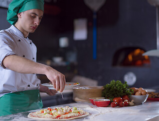 Image showing chef putting fresh vegetables on pizza dough