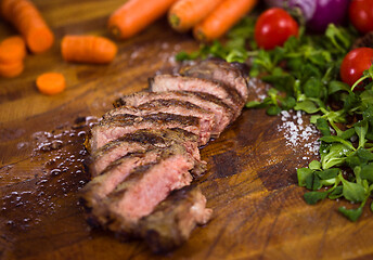 Image showing Juicy slices of grilled steak on wooden board