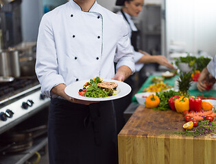 Image showing Chef holding dish of fried Salmon fish fillet