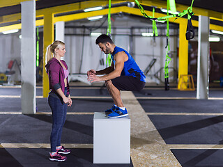Image showing woman working out with personal trainer jumping on fit box