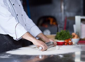 Image showing chef preparing dough for pizza with rolling pin