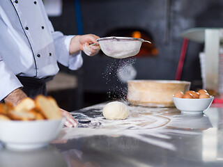 Image showing chef sprinkling flour over fresh pizza dough