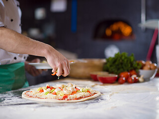 Image showing chef putting fresh vegetables on pizza dough