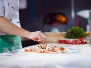 Image showing chef putting fresh mushrooms on pizza dough