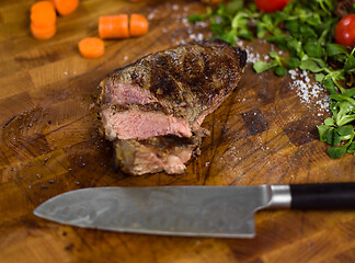 Image showing Juicy slices of grilled steak on wooden board