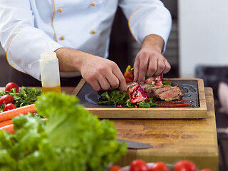 Image showing closeup of Chef hands serving beef steak