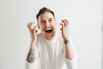 Image showing The young emotional angry man screaming on garay studio background