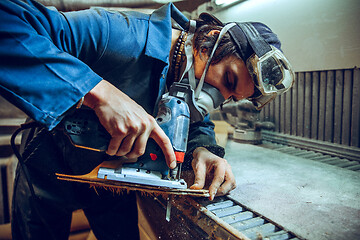 Image showing Carpenter using circular saw for cutting wooden boards.