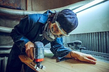 Image showing Carpenter using circular saw for cutting wooden boards.