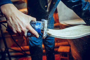 Image showing Carpenter using circular saw for cutting wooden boards.