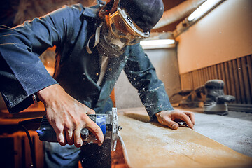 Image showing Carpenter using circular saw for cutting wooden boards.