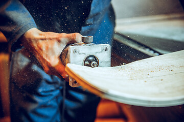 Image showing Carpenter using circular saw for cutting wooden boards.