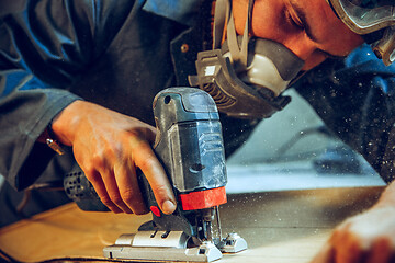 Image showing Carpenter using circular saw for cutting wooden boards.