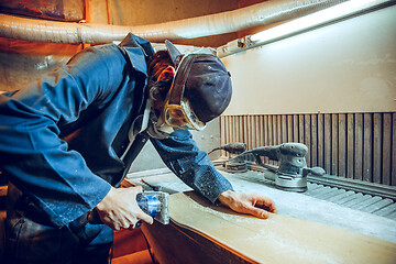 Image showing Carpenter using circular saw for cutting wooden boards.