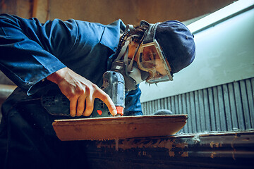 Image showing Carpenter using circular saw for cutting wooden boards.