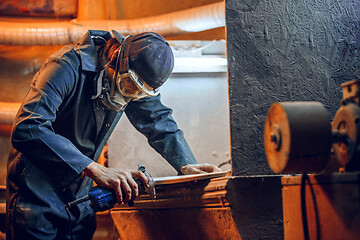 Image showing Carpenter using circular saw for cutting wooden boards.