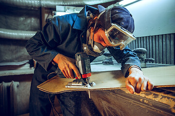 Image showing Carpenter using circular saw for cutting wooden boards.