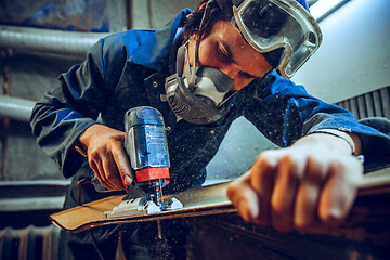 Image showing Carpenter using circular saw for cutting wooden boards.