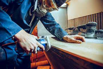 Image showing Carpenter using circular saw for cutting wooden boards.