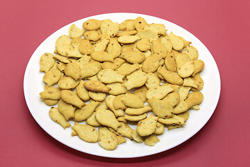 Image showing Fish-shaped cookies in a white plate on a crimson background 