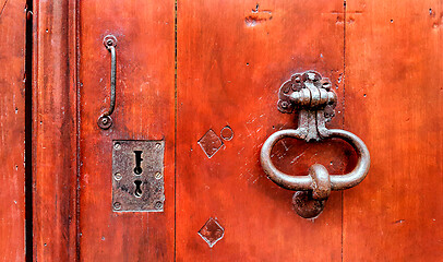 Image showing Vintage red wooden door with metallic doorhandle and keyholes