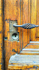 Image showing Vintage yellow wooden door with decorative handle and keyhole