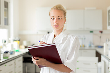 Image showing Portrait of young, confident female health care professional taking notes during inventory in scientific laboratory or medical doctors office