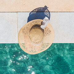 Image showing Woman wearing big summer sun hat relaxing on pier by clear turquoise sea.