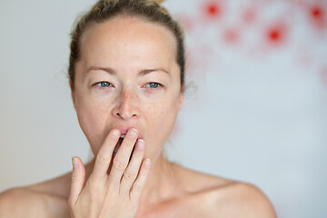 Image showing Closeup portrait headshot of sleepy young woman covering her wide open mouth while yawning by her palm. Face expression,emotion, body language concept